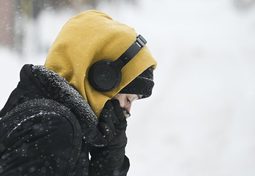 A person covers up during a snowstorm in Montreal, Sunday, February 16, 2025. A winter storm continues to strengthen in parts of Ontario and Quebec on Sunday as heavy snowfall is expected to blanket the provinces with a second big storm in just four days.THE CANADIAN PRESS/Graham Hughes
