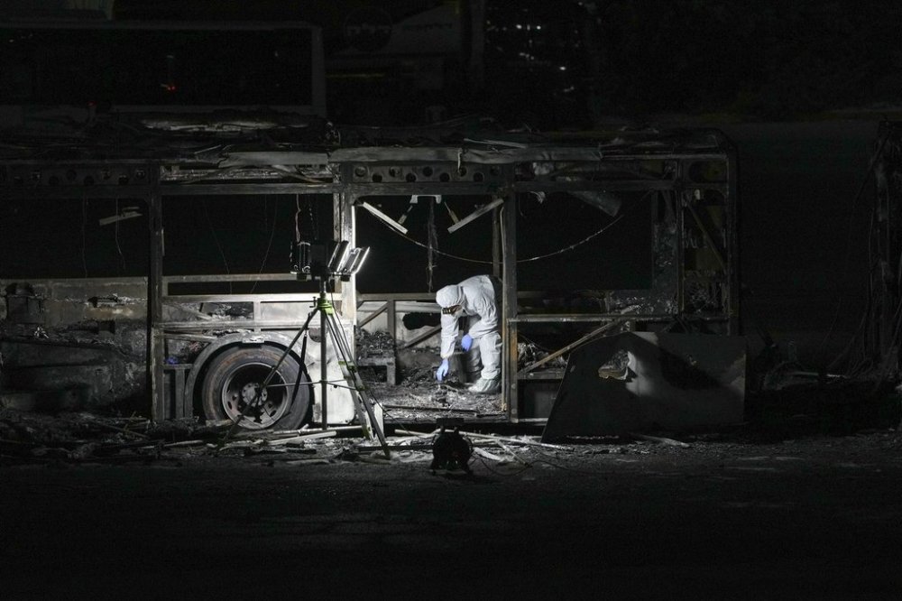 An Israeli police officer inspects the scene of one of a series of bus explosions in what authorities said appeared to be a militant attack in Bat Yam, central Israel, Thursday, Feb. 20, 2025. (AP Photo/Ohad Zwigenberg)