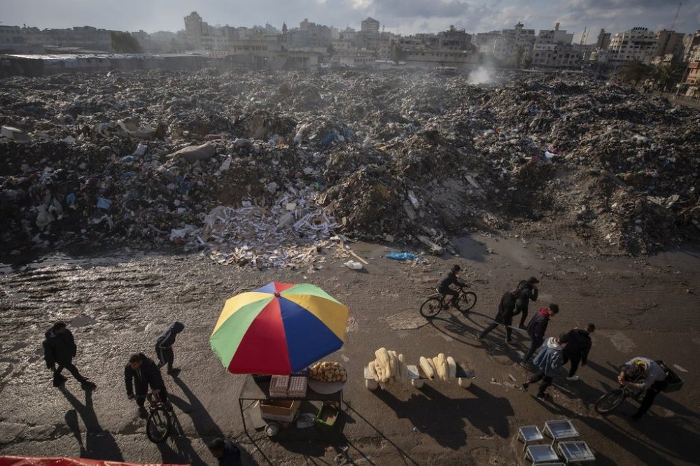 Palestinians walk past a pile of burning garbage, as there is no refuse collection in the city and people are disposing of their rubbish in the streets, in Gaza City, Wednesday, Feb. 12, 2025. (AP Photo/Jehad Alshrafi)