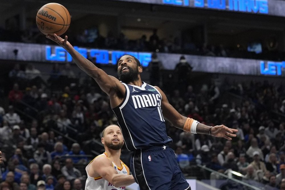 Dallas Mavericks guard Kyrie Irving (11) scores against Golden State Warriors guard Stephen Curry during the second half of an NBA basketball game in Dallas, Wednesday, Feb. 12, 2025. (AP Photo/LM Otero)