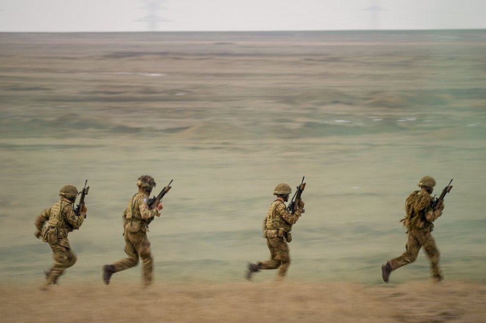 Servicemen run during the Steadfast Dart 2025 exercise, involving some 10,000 troops in three different countries from nine nations, representing the largest NATO operation planned this year, at a training range in Smardan, eastern Romania, Wednesday, Feb. 19, 2025. (AP Photo/Vadim Ghirda)