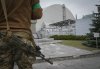 FILE - A Ukrainian soldier stands against the background of a shelter above the sarcophagus covering the exploded reactor at the Chernobyl nuclear power plant in Chernobyl, Ukraine, April 16, 2022. (AP Photo/Efrem Lukatsky, File)