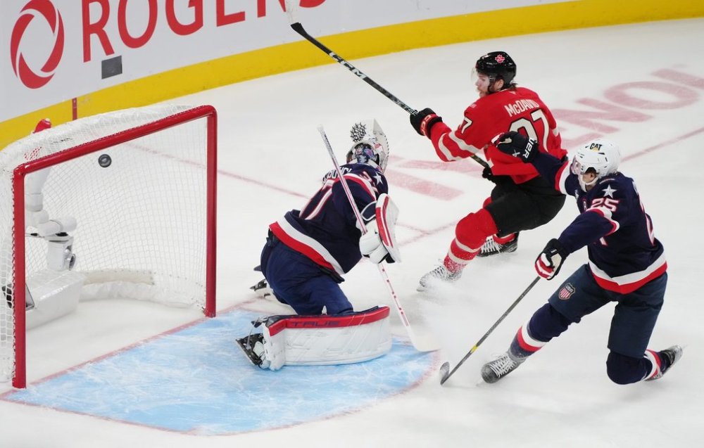 Canada's Connor McDavid (97) scores on United States goaltender Connor Hellebuyck (37) as United States' Charlie McAvoy (25) looks on during first period 4 Nations Face-Off hockey action in Montreal on Feb. 15, 2025. THE CANADIAN PRESS/Christinne Muschi