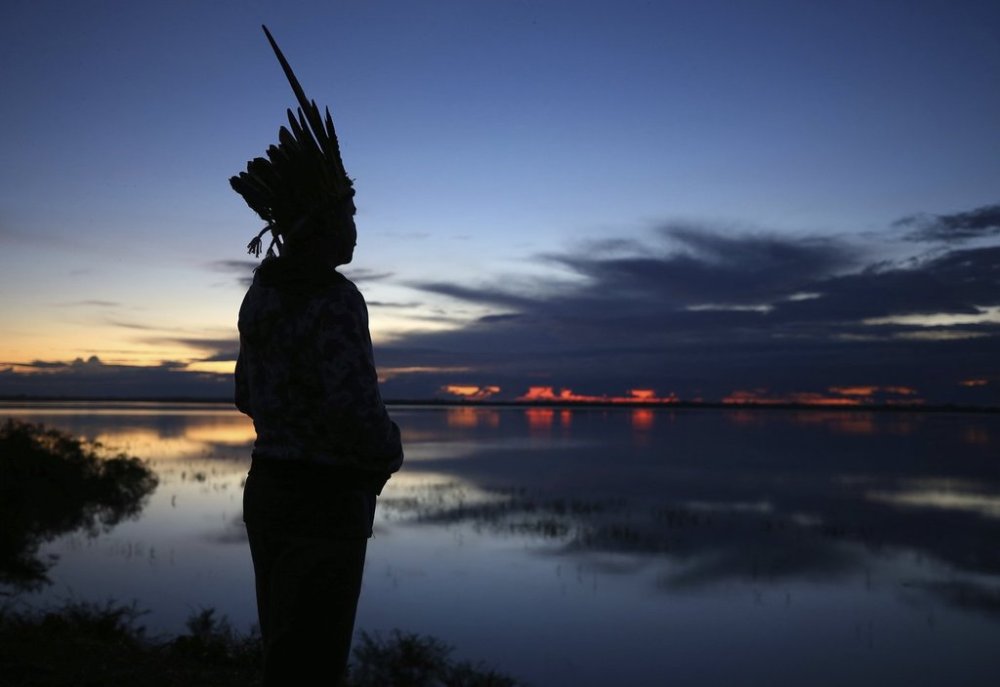 Robson Mura, of the Mura Indigenous community, watches the sunrise at the Moyray village in Autazes, Amazonas state, Brazil, Friday, Feb. 21, 2025. (AP Photo/Edmar Barros)