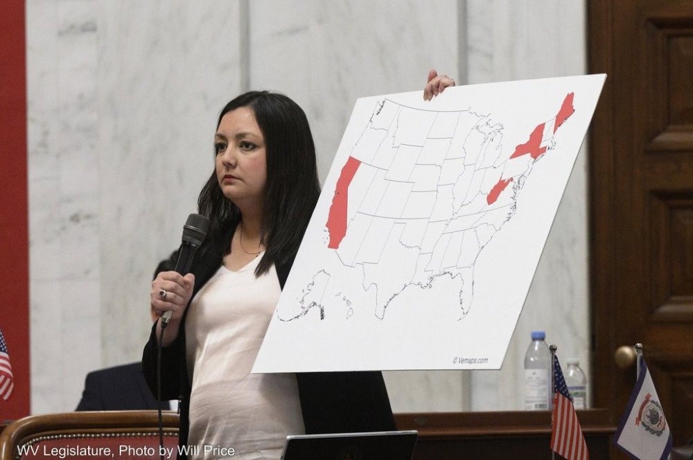 This photo provided by the West Virginia Legislature shows Republican Sen. Laura Wakim Chapman, chair of the West Virginia Senate Health and Human Resources Committee, holding a map of the U.S. on the Senate floor depicting the states, including West Virginia, that do not allow religious or philosophical exemptions for required school vaccinations, Friday, Feb. 21, 2025 in Charleston, West Virginia. (Will Price/West Virginia Legislature via AP)