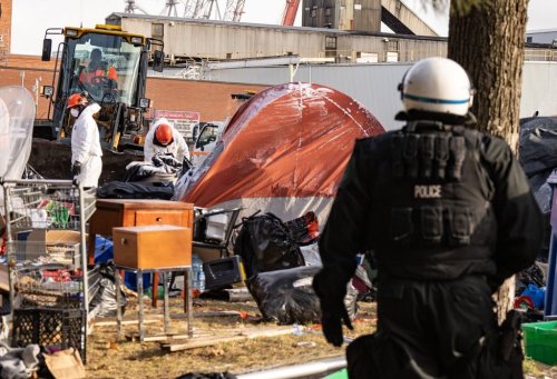 Police look on as workers from the Ministry of Transport dismantle a homeless encampment in Montreal, Monday, Dec. 2, 2024. THE CANADIAN PRESS/Christinne Muschi