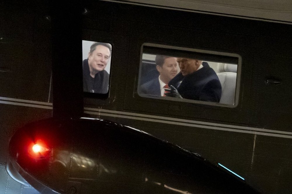 Elon Musk, left, and President Donald Trump, right, are seen through the windows as Marine One lands on the South Lawn of the White House, Wednesday, Feb. 19, 2025, in Washington. (AP Photo/Alex Brandon)