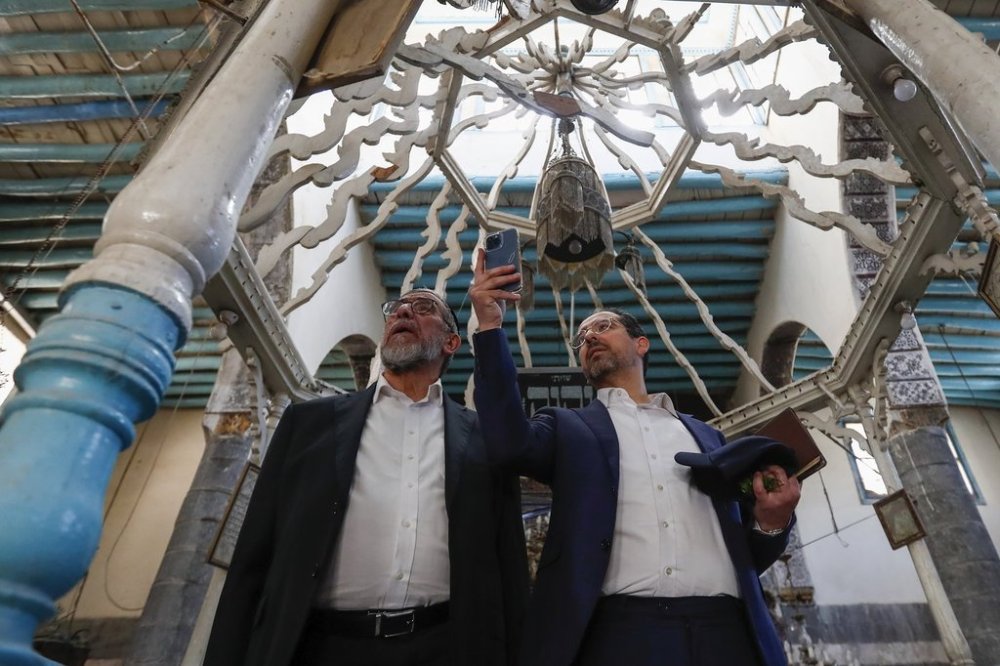Rabbi Yusuf Hamra, left, and his son Henry take pictures as they visit the Al-Raqi synagogue in the old city of Damascus Feb. 18, 2025. The Syrian-American Jewish family returned for the first time since emigrating from Syria to the United States more than three decades ago as part of a delegation organized by the Syrian Emergency Task Force, a U.S.-based nonprofit organization, in the wake of the fall of the government of former President Bashar Assad.(AP Photo/Omar Sanadiki)