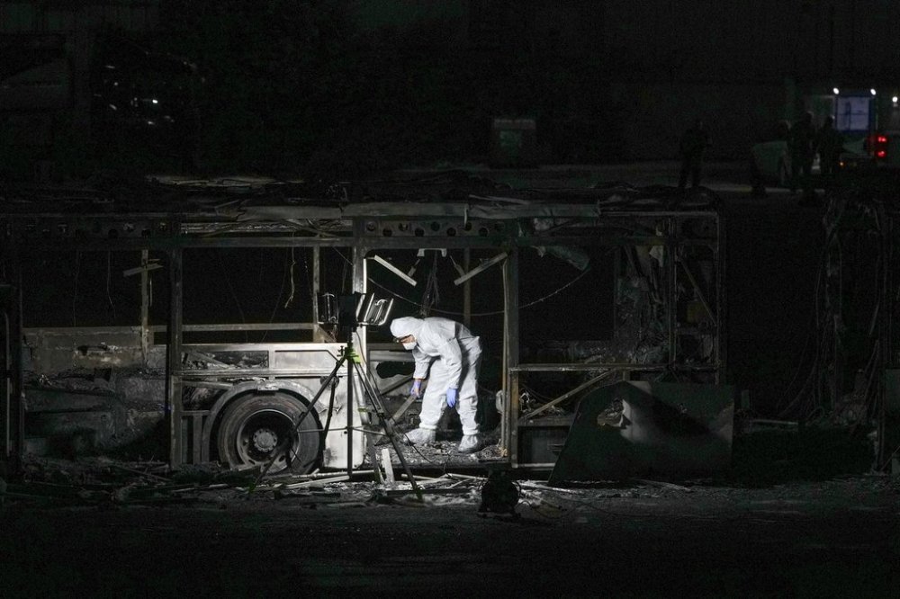 An Israeli police officer inspects the scene of one of a series of bus explosions in what authorities said appeared to be a militant attack in Bat Yam, central Israel, Thursday, Feb. 20, 2025. (AP Photo/Ohad Zwigenberg)