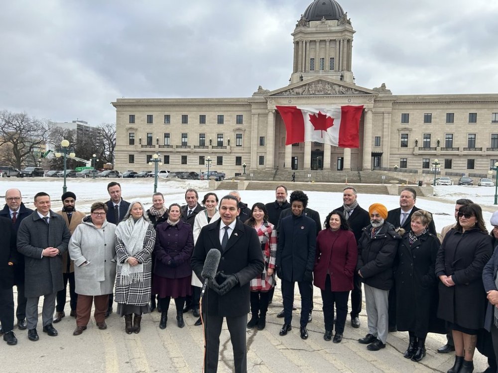 Premier Wab Kinew and members of his NDP caucus stand outside the legislative building for a press conference in Winnipeg on Tuesday, March 4, 2025. Politicians are returning to the Manitoba legislative chamber today amid the economic fallout from U.S. tariffs and ongoing challenges in provincial health care. THE CANADIAN PRESS/Steve Lambert