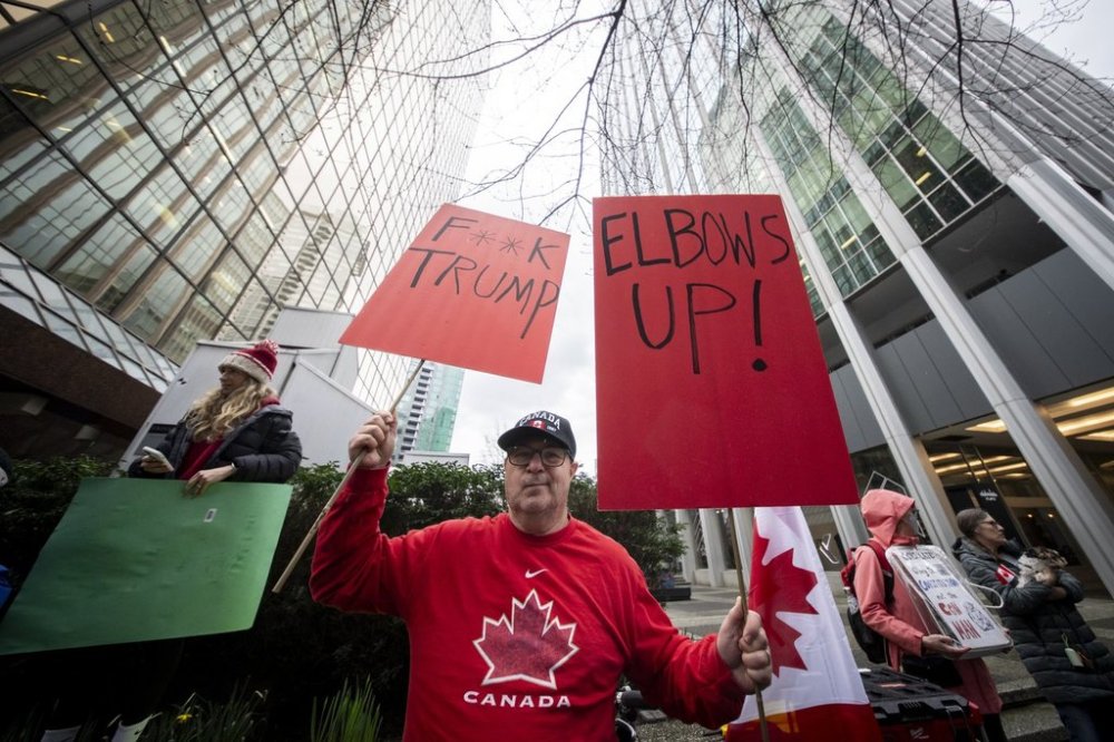 A demonstrator holds up signs during a protest outside of the U.S embassy in Vancouver B.C., on Tuesday, March 4, 2025. THE CANADIAN PRESS/Ethan Cairns