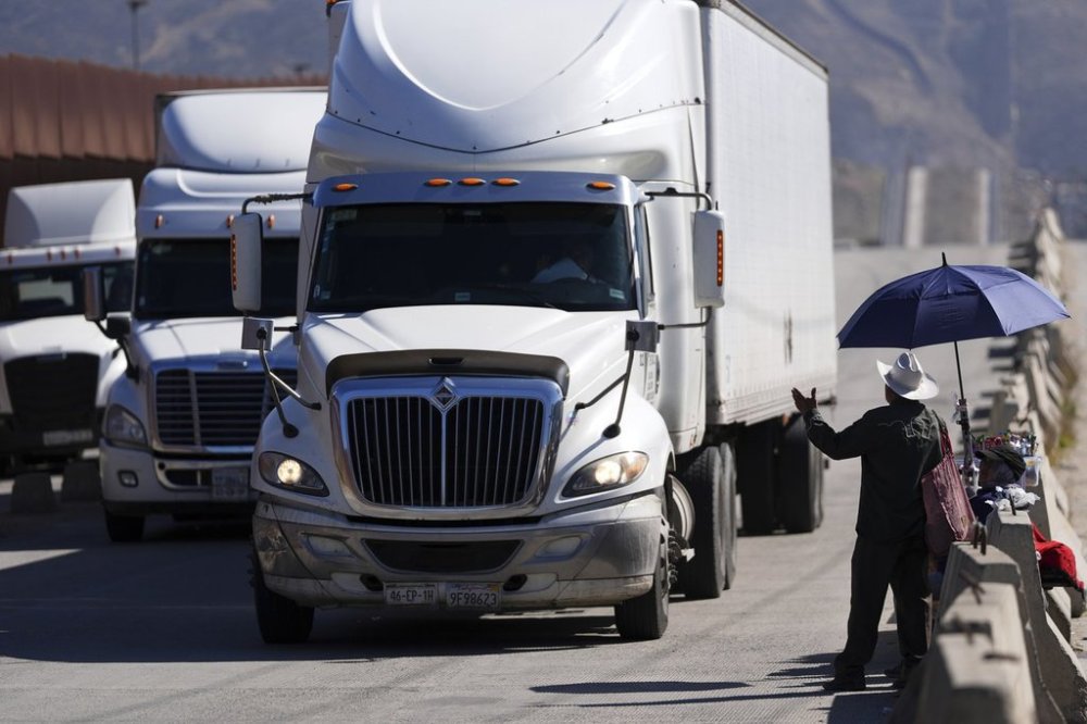 Susana Cordoba, right, gestures towards trucks lining up to cross the border into the United States as tariffs against Mexico go into effect, Tuesday, March 4, 2025, in Tijuana, Mexico. (AP Photo/Gregory Bull)
