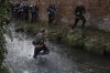A man runs with the ball in the Henmore Brook during annual Shrovetide medieval soccer match played in Ashbourne, England, Tuesday, March 4, 2025. (AP Photo/Darren Staples)
