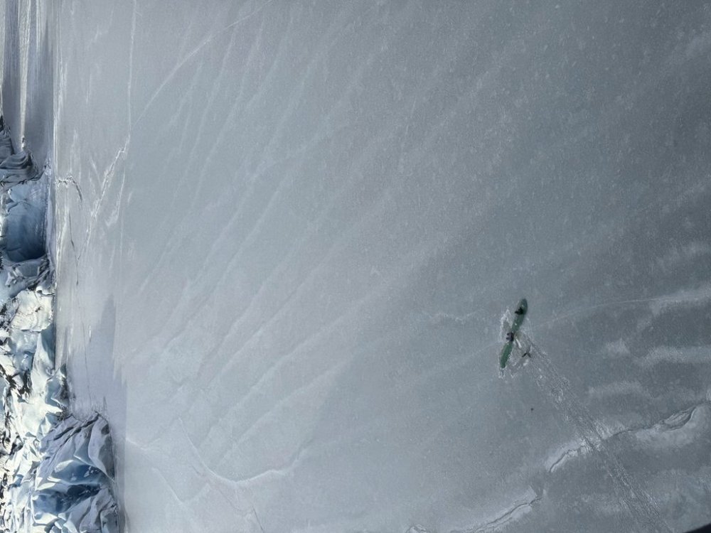 This photo provided Monday, March 24, 2025 by Dale Eicher shows an airplane partially submerged into the ice of Tustumena Lake near Soldotna, Alaska, with the three survivors standing on the plane's wing. (Dale Eicher via AP)