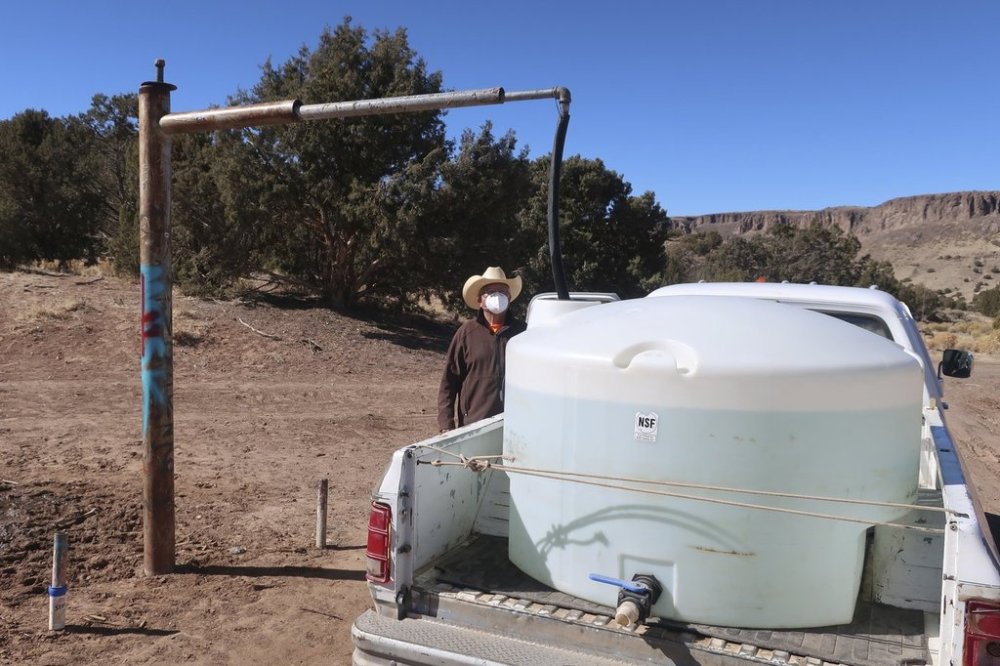 FILE - Phillip Yazzie waits for a water drum in the back of his pickup truck to be filled in Teesto, Ariz., on the Navajo Nation, on Feb. 11, 2021. (AP Photo/Felicia Fonseca, File)