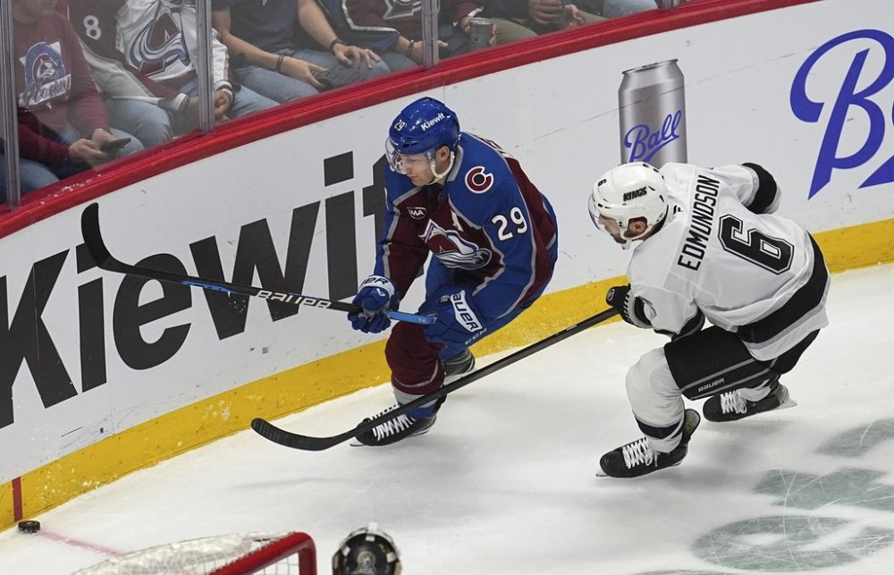 Colorado Avalanche center Nathan MacKinnon, left, pursues the puck with Los Angeles Kings defenseman Joel Edmundson in the first period of an NHL hockey game Thursday, March 27, 2025, in Denver. (AP Photo/David Zalubowski)