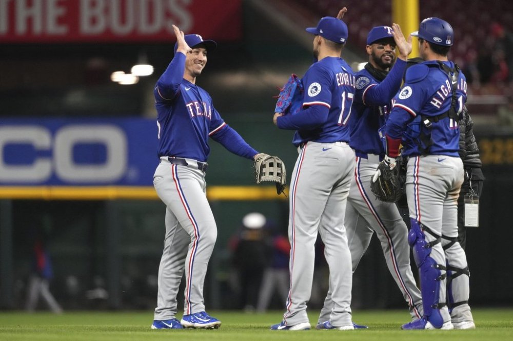 Texas Rangers' Wyatt Langford, center, high fives Nathan Eovaldi, center, at the conclusion of a baseball game against the Cincinnati Reds, Tuesday, April 1, 2025, in Cincinnati. (AP Photo/Kareem Elgazzar)