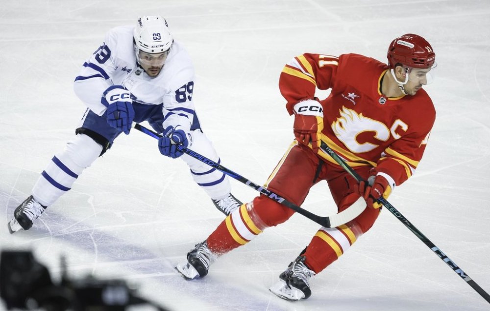Toronto Maple Leafs forward Nick Robertson, left, checks Calgary Flames captain Mikael Backlund during first-period NHL action in Calgary on Tuesday, Feb. 4, 2025. THE CANADIAN PRESS/Jeff McIntosh