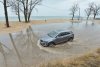 A car drives through a flooded section of road near Lions Park Beach Wednesday, April 2, 2025, in St. Joseph, Mich., after heavy storms moved through Southwest Michigan. (Don Campbell/The Herald-Palladium via AP)