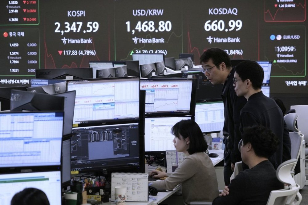 Currency traders watch monitors near a screen showing the Korea Composite Stock Price Index (KOSPI), top left, and the foreign exchange rate between U.S. dollar and South Korean won, top centre, at the foreign exchange dealing room of the KEB Hana Bank headquarters in Seoul, South Korea, Monday, April 7, 2025. (AP Photo/Ahn Young-joon)
