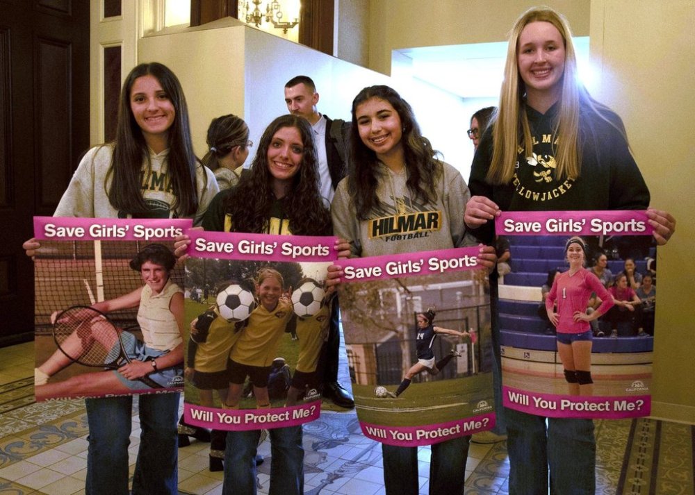 Student athletes hold signs during a hearing to consider bills to pass rules banning transgender student-athletes Tuesday, April 1, 2025, in Sacramento, Calif. (AP Photo/Yuri Avila)