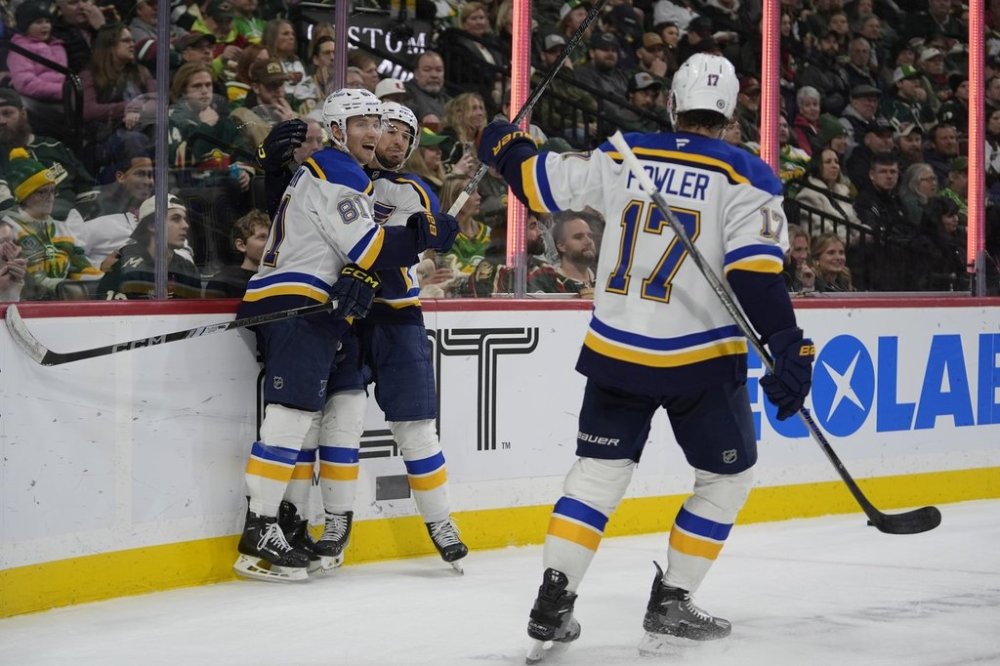 St. Louis Blues center Jordan Kyrou (25), middle, celebrates with center Dylan Holloway (81) and defenseman Cam Fowler (17) after scoring a goal during the second period of an NHL hockey game against the Minnesota Wild, Saturday, March 15, 2025, in St. Paul, Minn. (AP Photo/Abbie Parr)