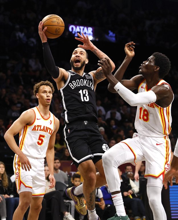 Brooklyn Nets guard Tyrese Martin (13) drives to the basket against Atlanta Hawks forward Mouhamed Gueye (18) and guard Dyson Daniels (5) during the first half of an NBA basketball game, Sunday, March 16, 2025, in New York. (AP Photo/Noah K. Murray)