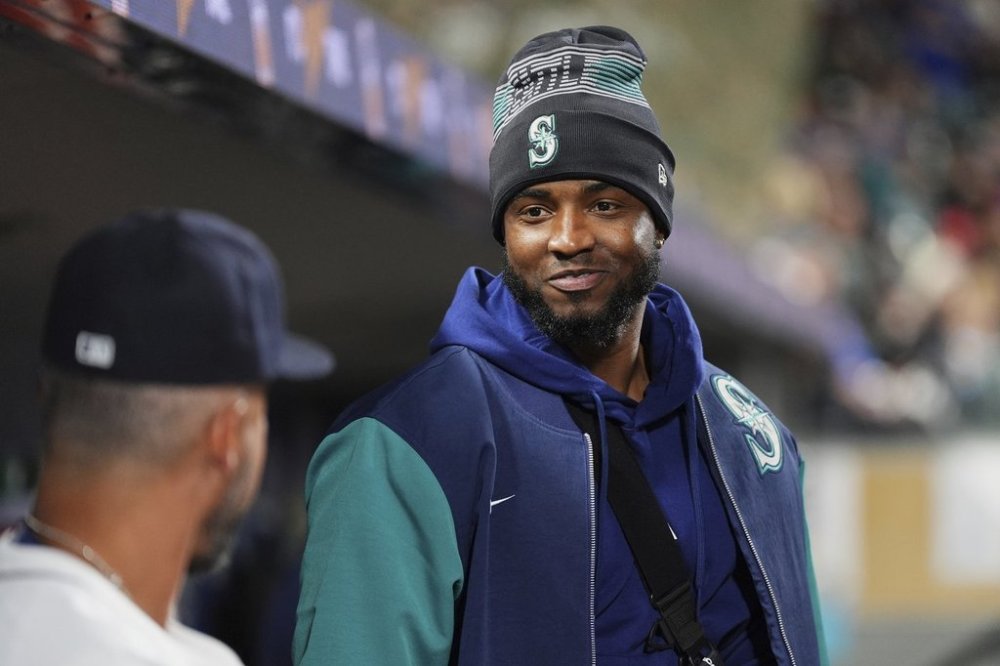 Seattle Mariners' Victor Robles talks with third base coach Kristopher Negrón, left, in the dugout during a baseball game against the Houston Astros, Monday, April 7, 2025, in Seattle. (AP Photo/Lindsey Wasson)