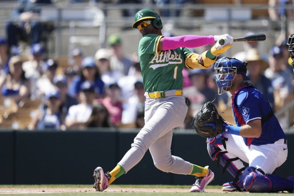 FILE - Athletics' Esteury Ruiz (1) follows through with his swing as Los Angeles Dodgers catcher Austin Barnes, right, looks on during the first inning of a spring training baseball game Sunday, March 9, 2025, in Phoenix. (AP Photo/Ross D. Franklin,File)