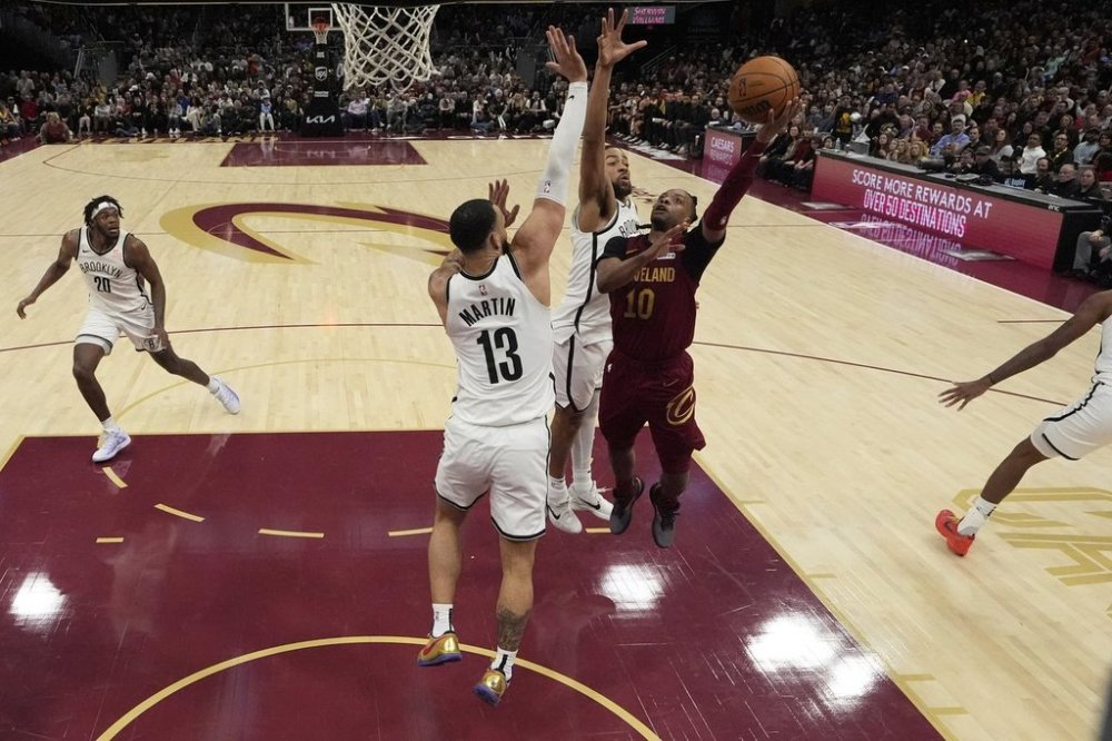 Cleveland Cavaliers guard Darius Garland (10) shoots as Brooklyn Nets guard Tyrese Martin (13) and forward Trendon Watford, center, defend in the second half of an NBA basketball game, Tuesday, March 11, 2025, in Cleveland. (AP Photo/Sue Ogrocki)
