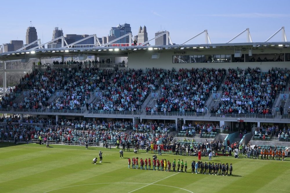 FILE - With the skyline of Kansas City behind them, the Kansas City Current and the Portland Thorns FC line up before the start of an NWSL soccer match at the new CPKC Stadium, March 16, 2024, in Kansas City, Mo. (AP Photo/Reed Hoffmann, File)