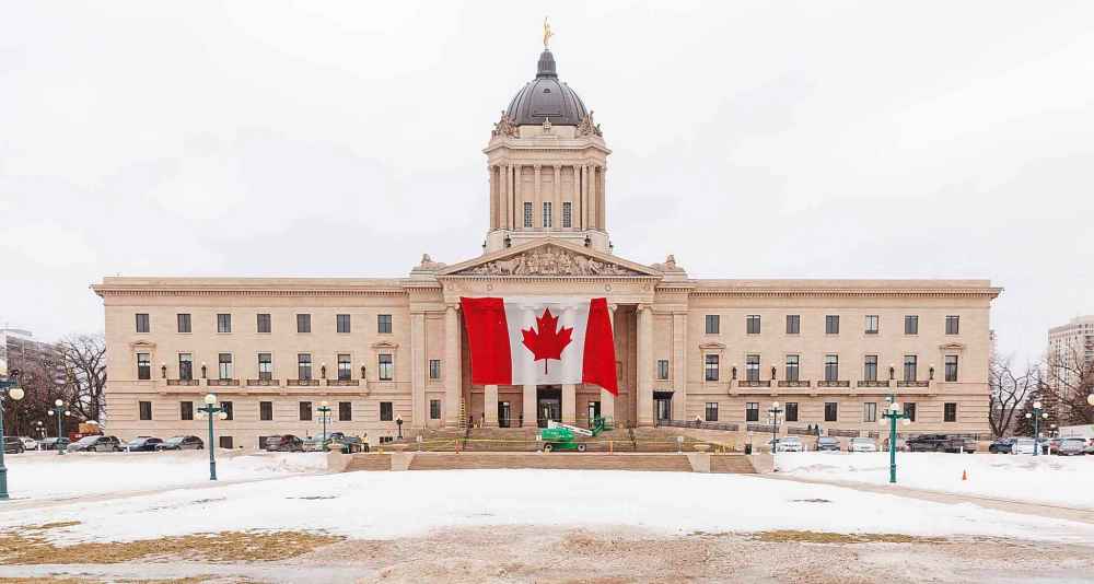 A giant Canadian flag is installed Tuesday morning on the front of the Manitoba legislative building, hours after U.S. President Donald Trump's tariffs on Canadian products came into effect. Manitoba’s blueprint for the coming fiscal year will be unveiled March 20. (Mike Deal / Free Press)