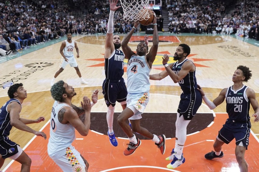 San Antonio Spurs guard De'Aaron Fox (4) scores past Dallas Mavericks forward Caleb Martin (16) during the second half of an NBA basketball game in San Antonio, Wednesday, March 12, 2025. (AP Photo/Eric Gay)