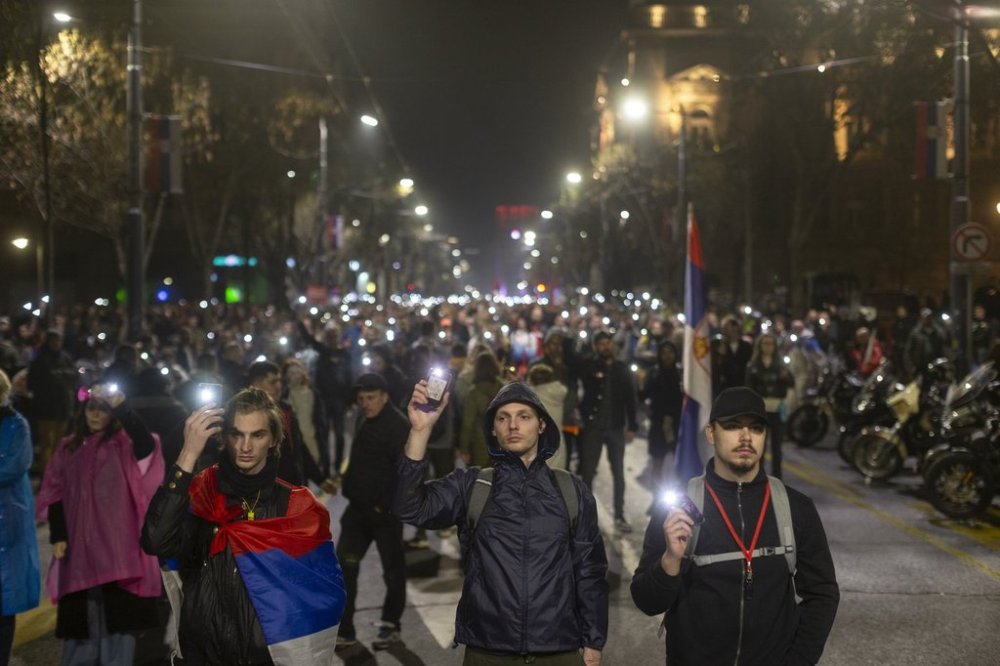 People use the lights on their cell phones as they observe fifteen minutes of silence during a major anti-corruption rally led by university students in Belgrade, Serbia, Saturday, March 15, 2025. (AP Photo/Marko Drobnjakovic)