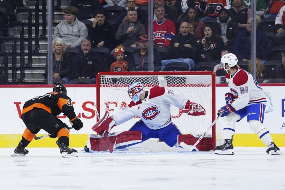 Philadelphia Flyers' Matvei Michkov, left, scores past Montreal Canadiens goaltender Jakub Dobes, center, during the first period of an NHL hockey game, Thursday, March 27, 2025, in Philadelphia. (AP Photo/Derik Hamilton)