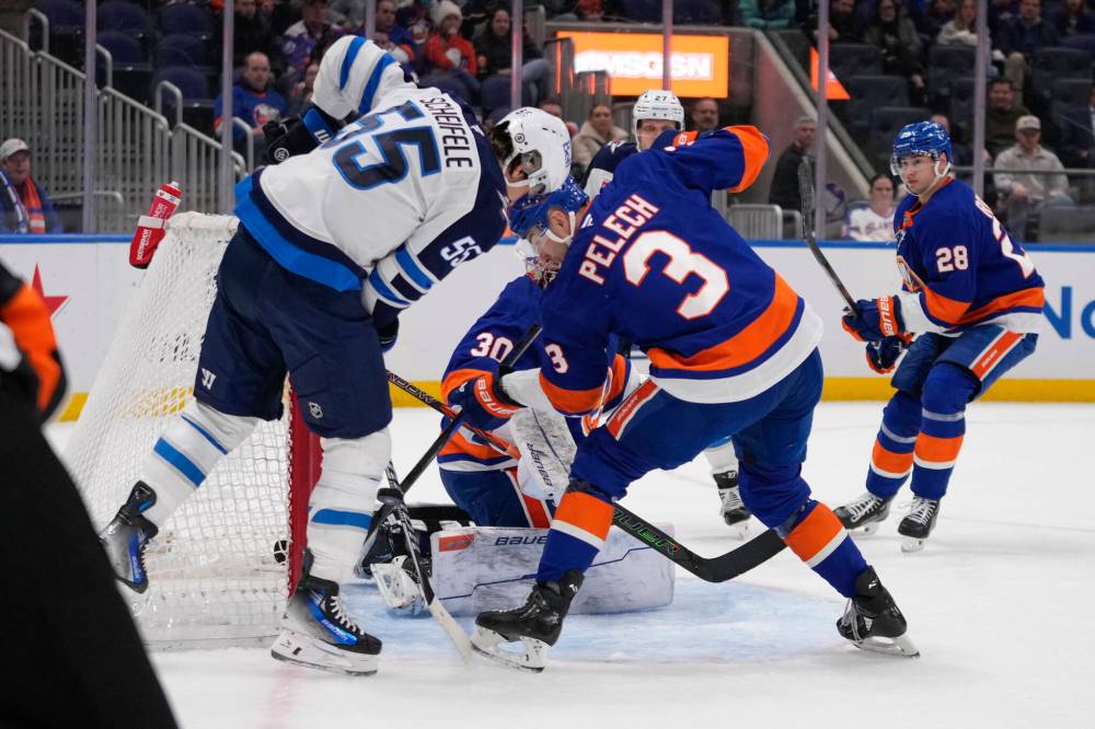 Frank Franklin II / The Associated Press
Islanders’ Adam Pelech fights for control of the puck with the Jets’ Mark Scheifele during the first period.