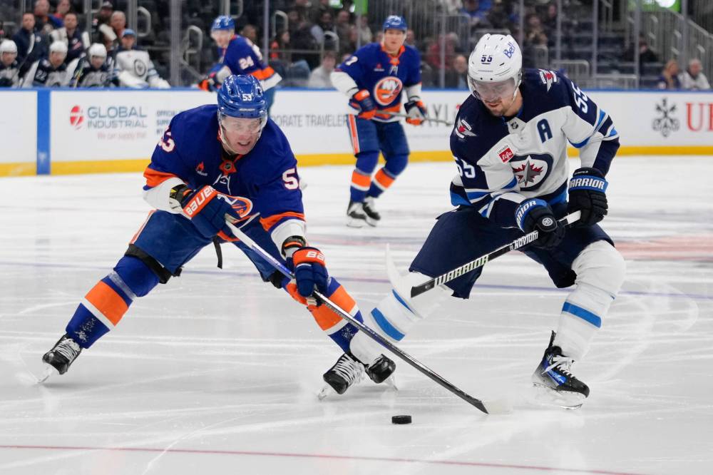 Frank Franklin II / The Associated Press
Casey Cizikas (left) of the Islanders and the Jets’ Mark Scheifele battle for the puck Tuesday night in Elmont, N.Y.