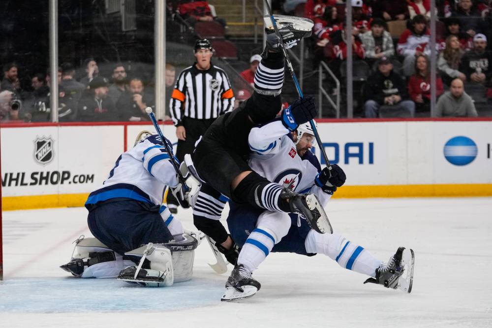 Frank Franklin II / The Associated Press
D-man Dylan DeMelo gives Devils forward Timo Meier the what-for Friday night while Connor Hellebuyck minds the twine during the Jets 6-1 victory in New Jersey.