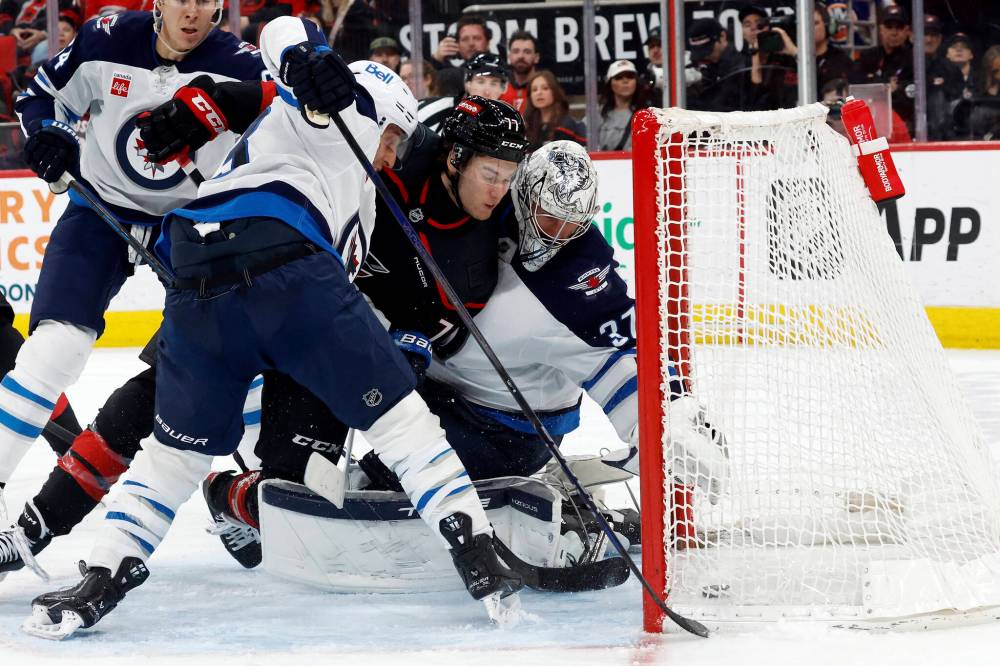 Carolina Hurricanes’ Mark Jankowski (77) pushes the puck past Winnipeg Jets goaltender Connor Hellebuyck (37) for a goal during the second period. (Karl DeBlaker / The Associated Press)