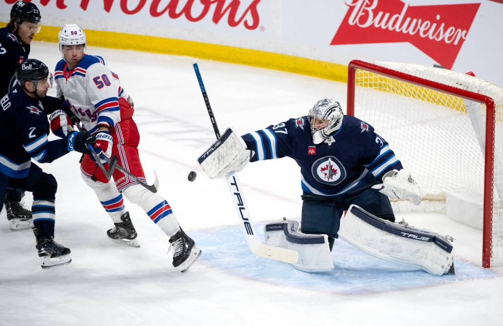 Fred Greenslade / THE CANADIAN PRESS
Jets goaltender Connor Hellebuyck makes one of his 21 saves Tuesday night against the New York Rangers.