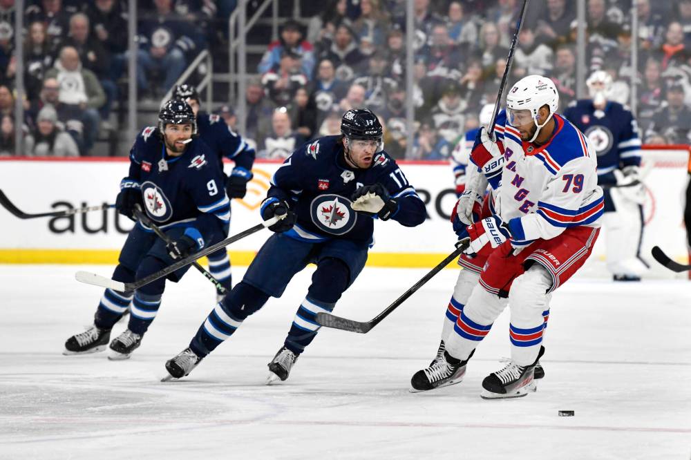 Fred Greenslade / THE CANADIAN PRESS
The Rangers’ K’Andre Miller and Jets’ Adam Lowry chase a loose puck during the second period.