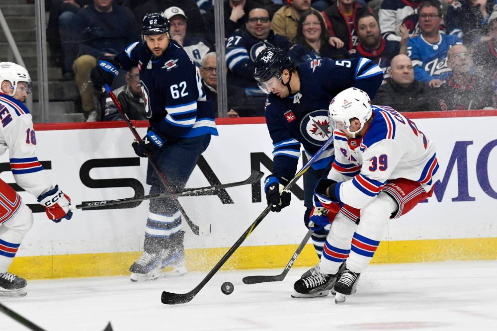 Fred Greenslade / THE CANADIAN PRESS
The Rangers’ Sam Carrick and Jets’ Luke Schenn battle for the puck during the second period.