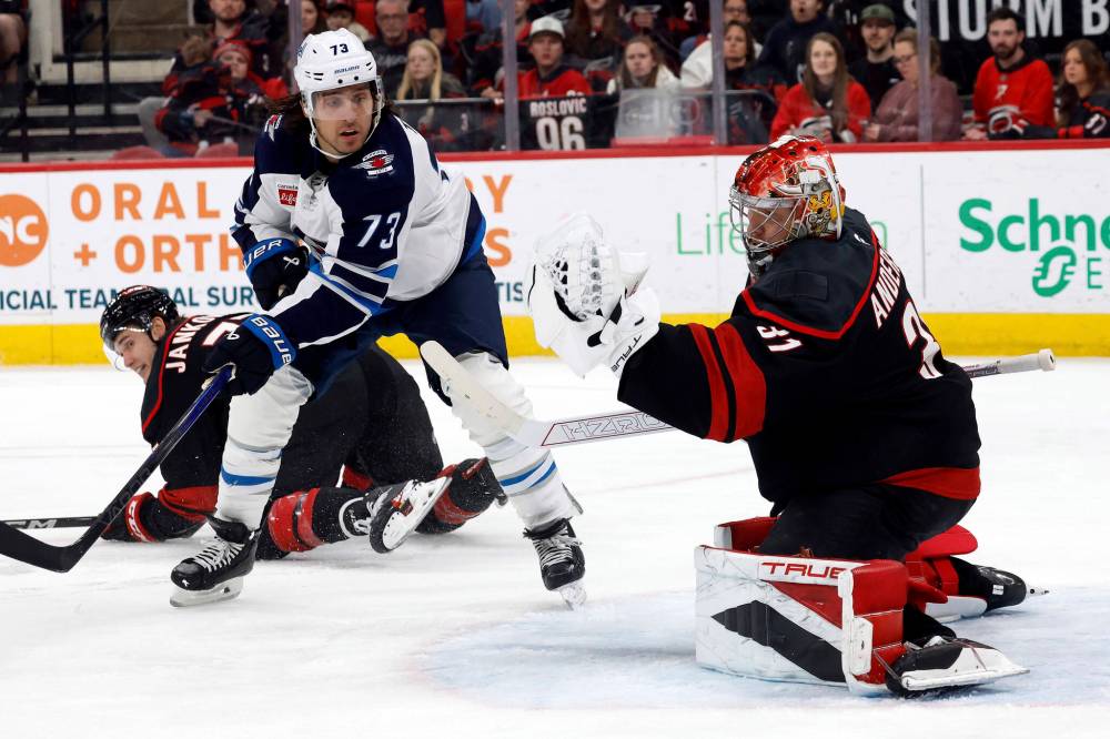 Brandon Tanev (centre) has his deflection snared by Carolina Hurricanes goaltender Frederik Andersen (right) during first period action on March 9 in Raleigh, N.C. (Karl DeBlaker / The Associated Press)