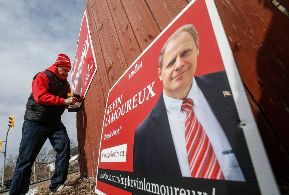 JOHN WOODS / FREE PRESS
Liberal candidate Kevin Lamoureux, hangs signs on a house fence on Selkirk at Keewatin on Sunday.