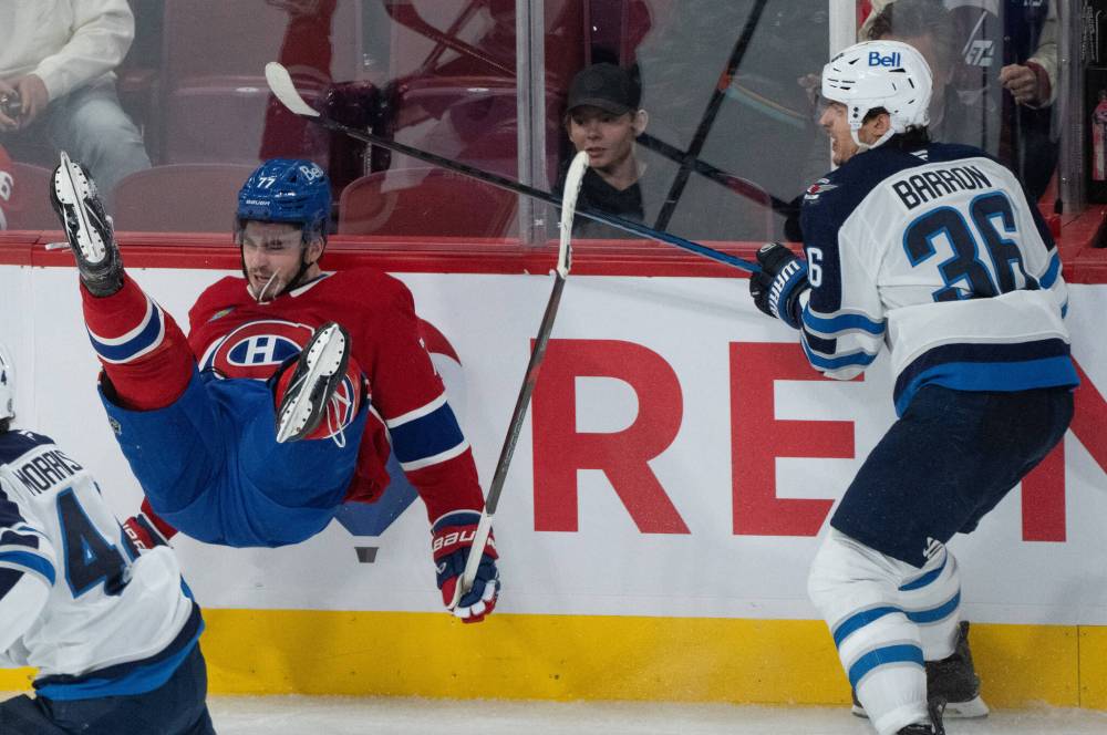 Montreal Canadiens’ Kirby Dach (77) is checked into the boards by Winnipeg Jets’ Morgan Barron (36) during third period NHL hockey action in Montreal on January 28. (Christinne Muschi / The Canadian Press files)