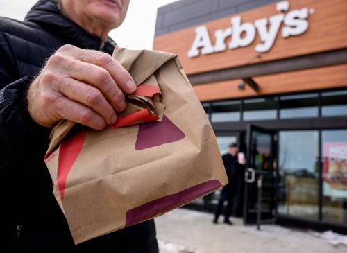 MIKE SUDOMA / FREE PRESS A happy customer holds up a paper bag full of food from the new Arby’s in the Seasons of Tuxedo neighbourhood located at 753 Sterling Lyon Parkways Sunday afternoon Neighbourhood March 30, 2025
