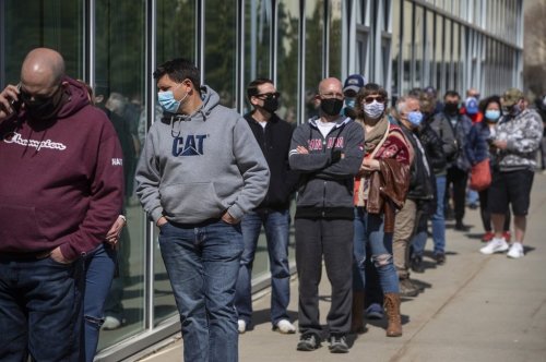 People line up outside an immunization clinic to get their Oxford-AstraZeneca COVID-19 vaccine in Edmonton, Tuesday, April 20, 2021. THE CANADIAN PRESS/Jason Franson