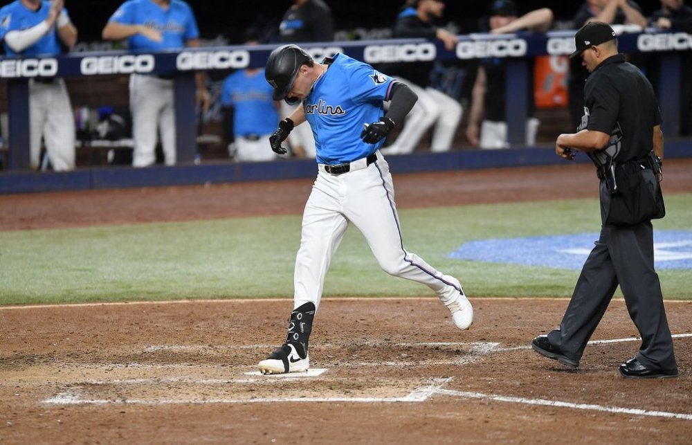 Miami Marlins' Griffin Conine ,left, scores during the eighth inning of a baseball game against the Pittsburgh Pirates, Sunday, March 30, 2025, in Miami. (AP Photo/Michael Laughlin)
