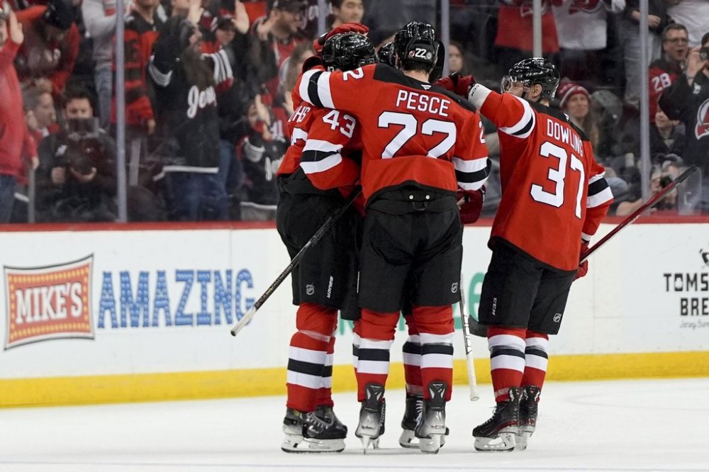 New Jersey Devils defenseman Luke Hughes (43), left, celebrates with center Justin Dowling (37), right, and defenseman Brett Pesce (22), center, after scoring a goal during the first period of an NHL hockey game against the Minnesota Wild, Monday, March 31, 2025, in Newark, N.J. (AP Photo/Julia Demaree Nikhinson)