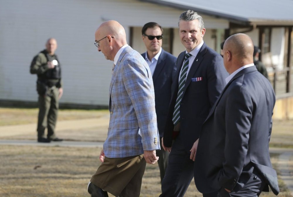 Secretary of Defense Pete Hegseth, center, walks with Scott Burns, left, as they enter